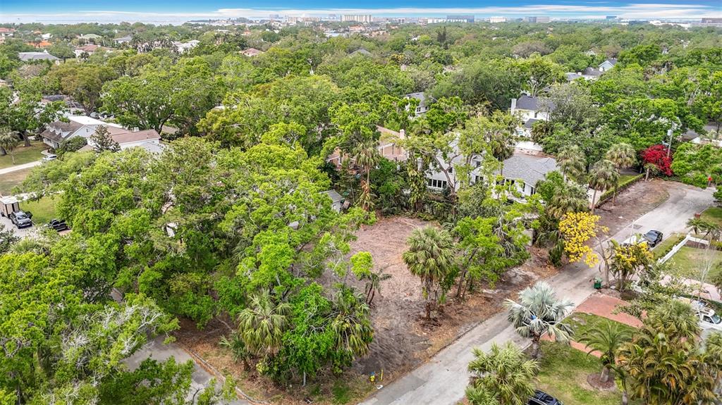 An aerial view shows a vacant, cleared residential lot surrounded by mature trees and houses — 4701 W CLEAR AVENUE, TAMPA, FL