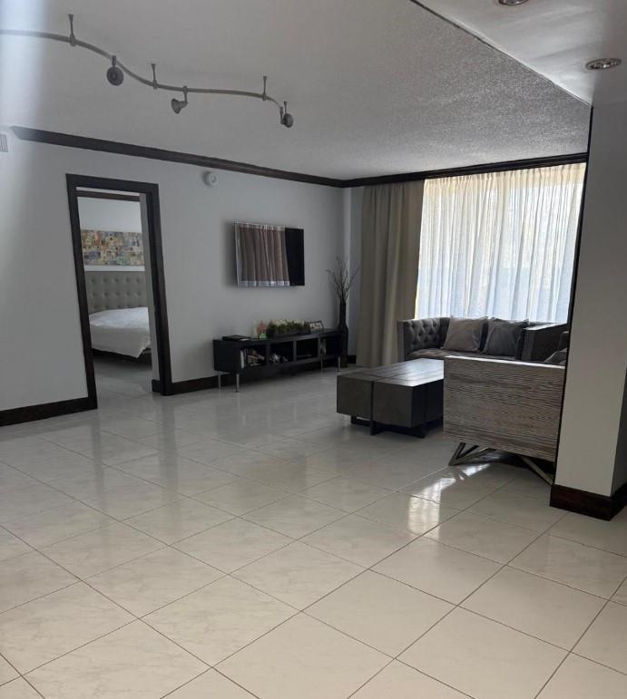 A living room with white tile floors, a dark media console, and a gray sofa — 1833 S Ocean Drive # 1209, FL 33009, FL