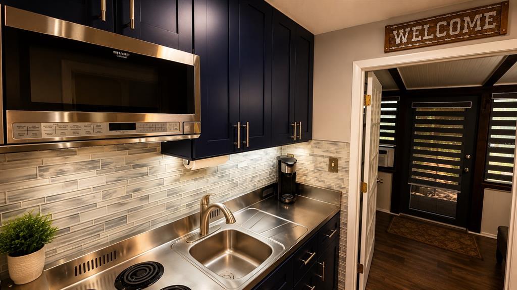 A kitchen with dark blue cabinets, stainless steel countertops, and a microwave above the sink — 3200 RIVER RANCH BOULEVARD UNIT 303, LAKE WALES, FL