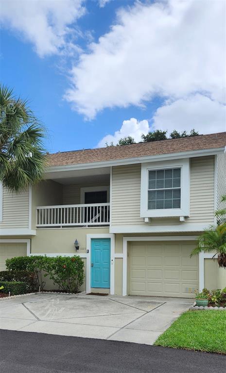 A two-story townhouse with beige siding, a turquoise front door, and a single-car garage — 12223 SUN VISTA COURT E, TREASURE ISLAND, FL