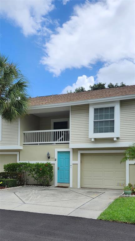 A two-story townhouse exterior features light siding, a turquoise front door, and a second-floor balcony — 12223 SUN VISTA COURT E, TREASURE ISLAND, FL