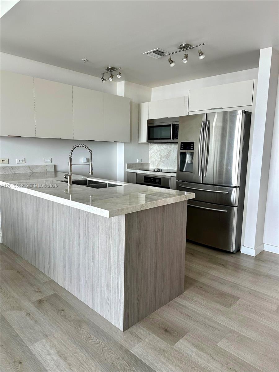 A modern kitchen features a central island, stainless steel appliances, and light-toned cabinetry — 3301 NE 1st Ave # H1811, Miami FL 33137, MIAMI, FL