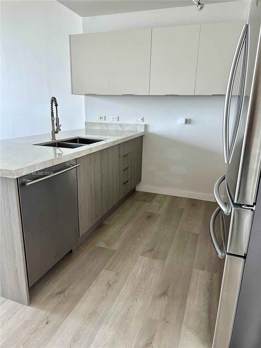 A modern kitchen features light wood cabinets, stainless steel appliances, and a stone countertop — 3301 NE 1st Ave # H1811, Miami FL 33137, MIAMI, FL