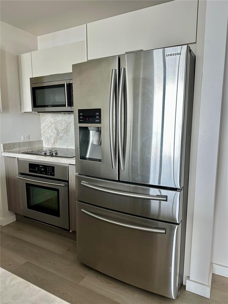 A modern kitchen features stainless steel appliances, white cabinetry, and a marble-patterned backsplash — 3301 NE 1st Ave # H1811, Miami FL 33137, MIAMI, FL