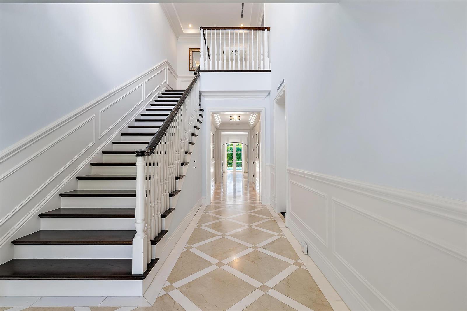 A grand foyer features a dark wood staircase, white wainscoting, and a diamond-patterned stone floor — 210 Emerald Lane, Palm Beach FL 33480, PALM BEACH, FL