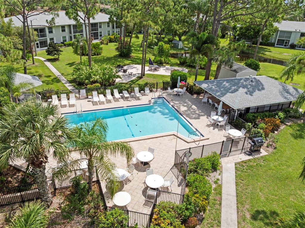 An aerial view of a community swimming pool surrounded by lounge chairs, tables, and landscaping — 7104 NANTUCKET CIRCLE UNIT 3, NORTH FORT MYERS, FL