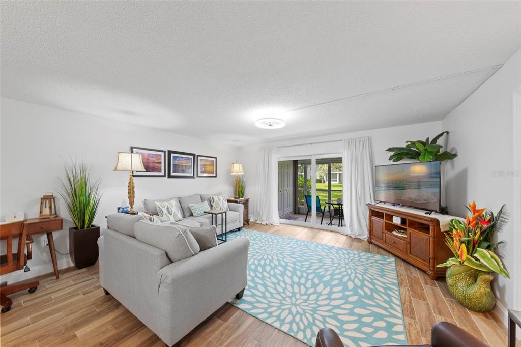 A living room with a gray sofa, blue patterned rug, and sliding glass patio doors — 7104 NANTUCKET CIRCLE UNIT 3, NORTH FORT MYERS, FL