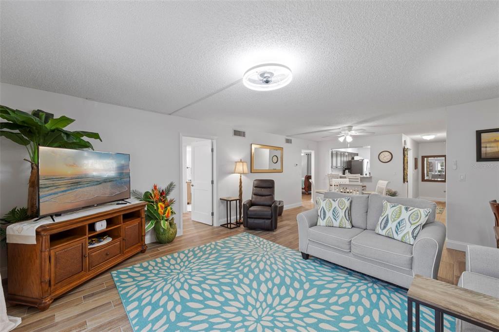 A living room features a blue patterned rug, a gray sofa, and a wooden media console — 7104 NANTUCKET CIRCLE UNIT 3, NORTH FORT MYERS, FL