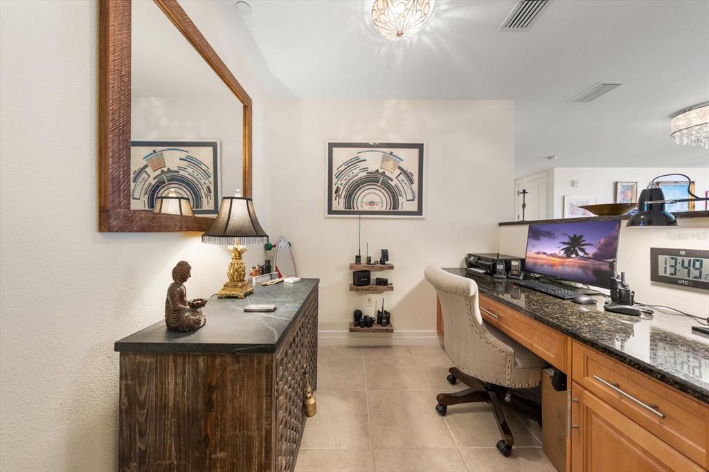 A home office features a granite-topped desk, a wooden cabinet, and wall-mounted shelving — 331 CLEVELAND ST UNIT #301, CLEARWATER, FL