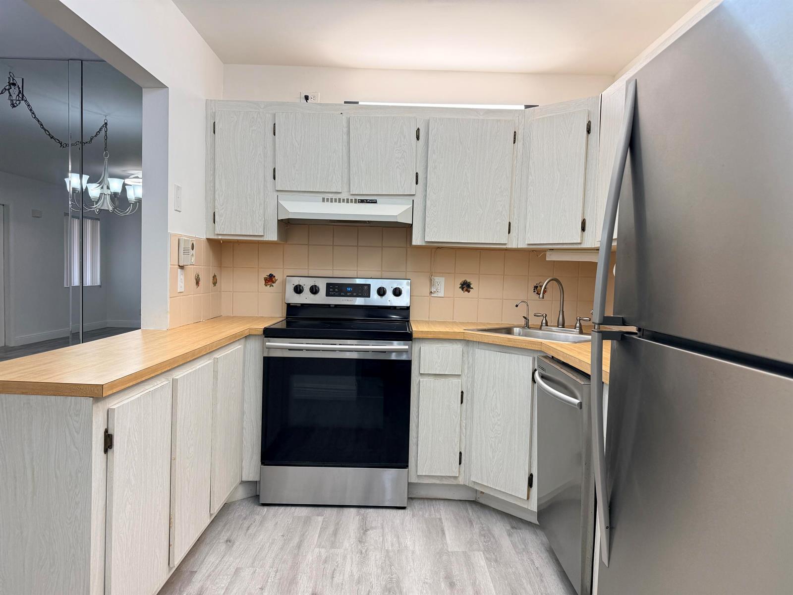 A kitchen features light wood-grain cabinets, stainless steel appliances, and tan tile backsplashes — 318 Knotty Pine Circle # 2, FL 33463, FL
