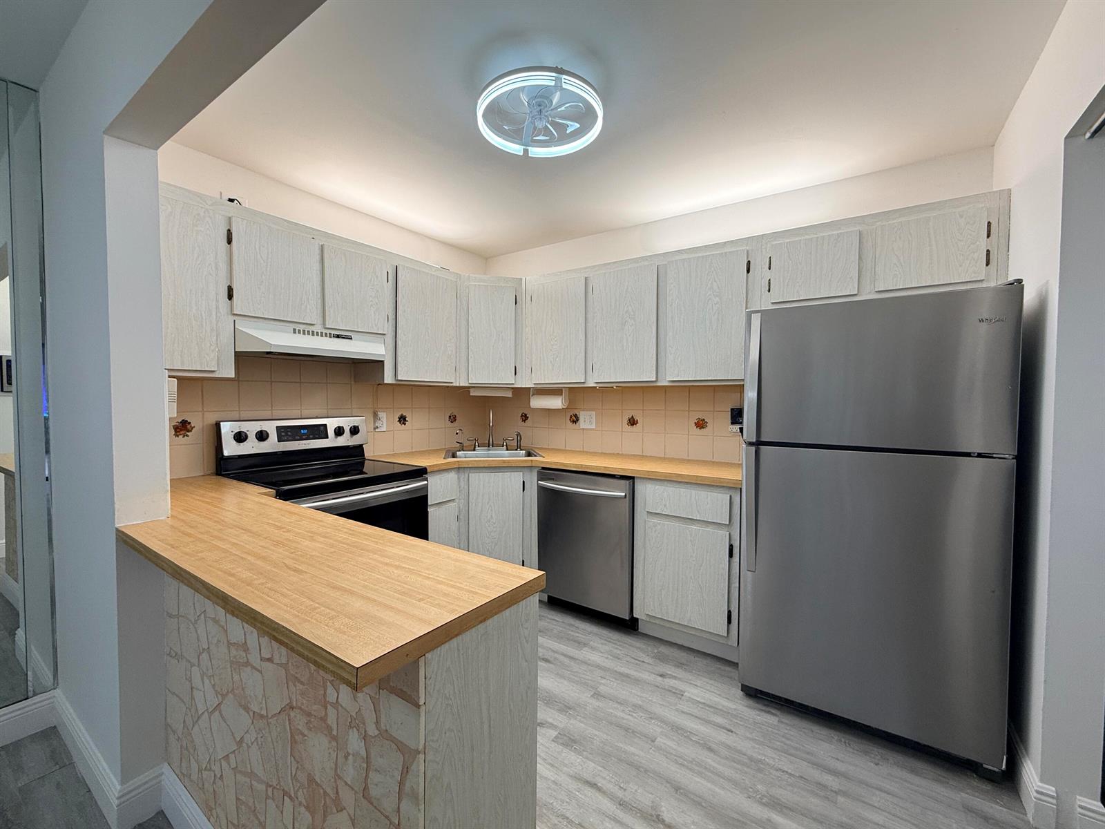 A kitchen features light wood-grain cabinets, a stainless steel refrigerator, and a wood-look countertop — 318 Knotty Pine Circle # 2, FL 33463, FL