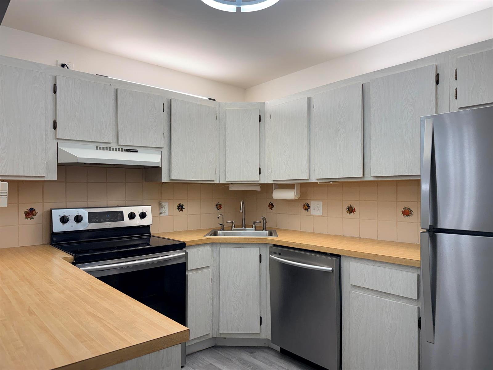 A kitchen features light-colored wood-grain cabinets, a butcher block countertop, and stainless steel appliances — 318 Knotty Pine Circle # 2, FL 33463, FL