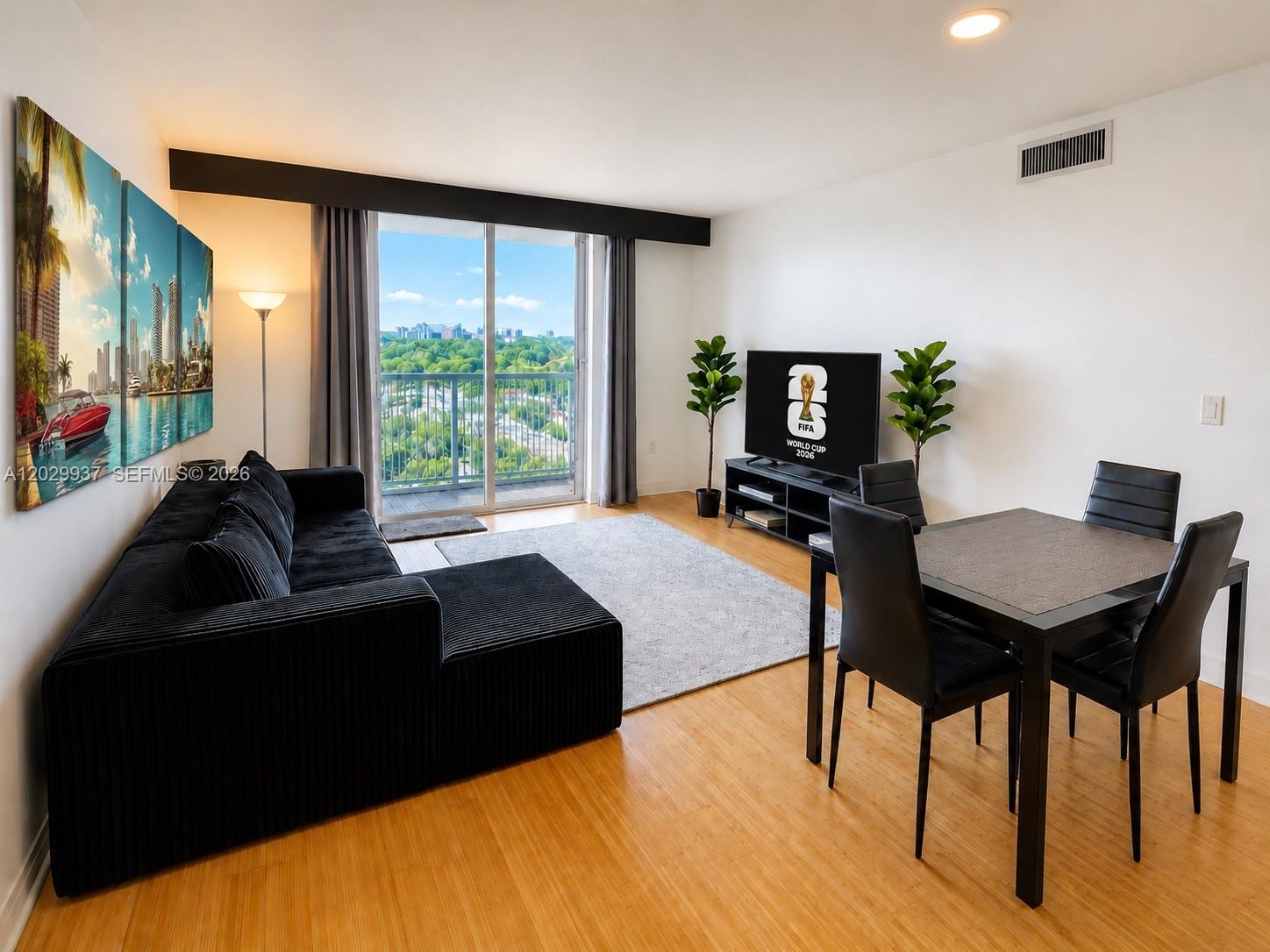 A living and dining area features a black sectional sofa, dining set, and balcony view — 900 SW 8th St # 1103, Miami FL 33130, MIAMI, FL