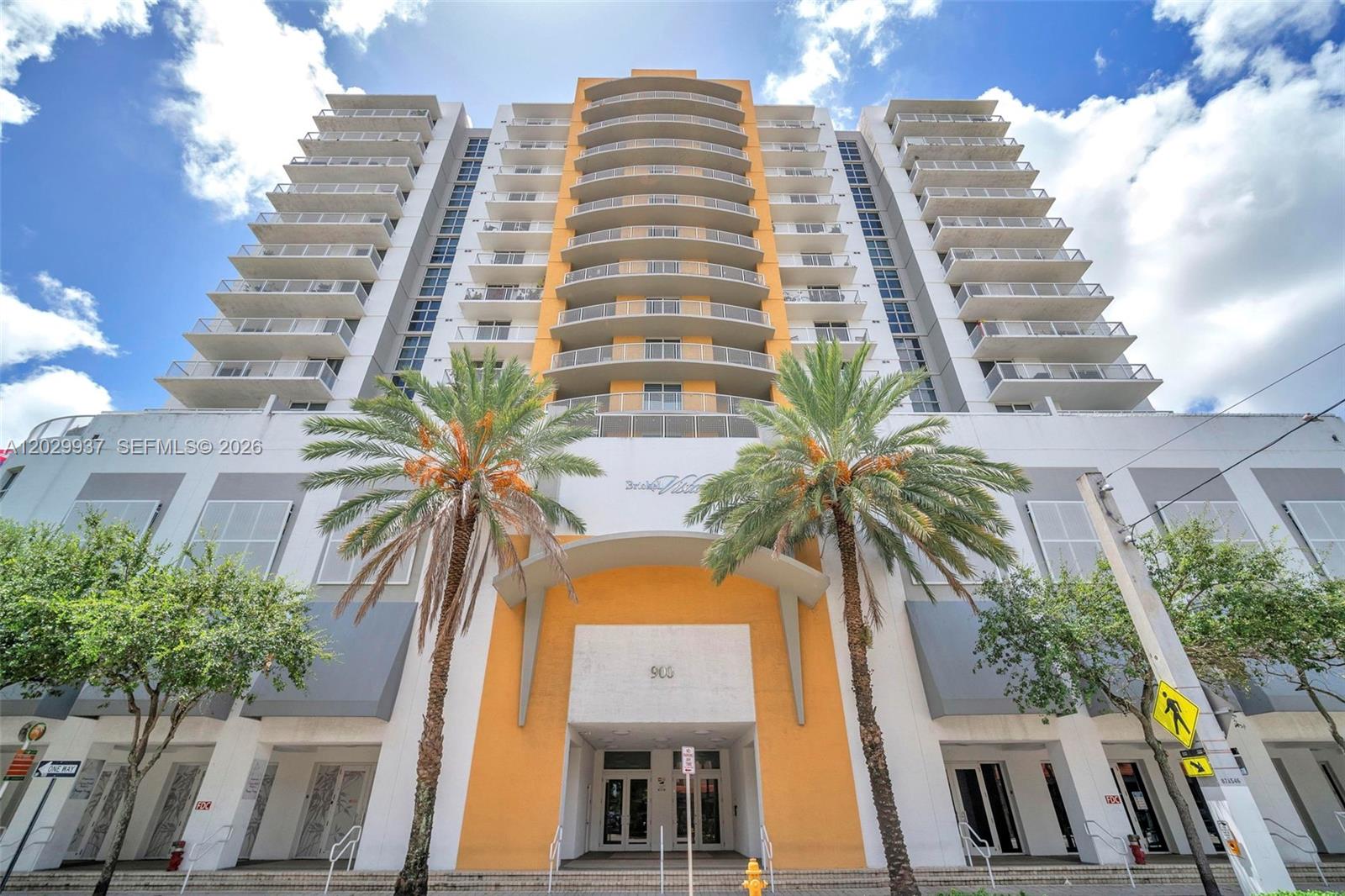 A low-angle view of a multi-story residential building with balconies and two palm trees — 900 SW 8th St # 1103, Miami FL 33130, MIAMI, FL