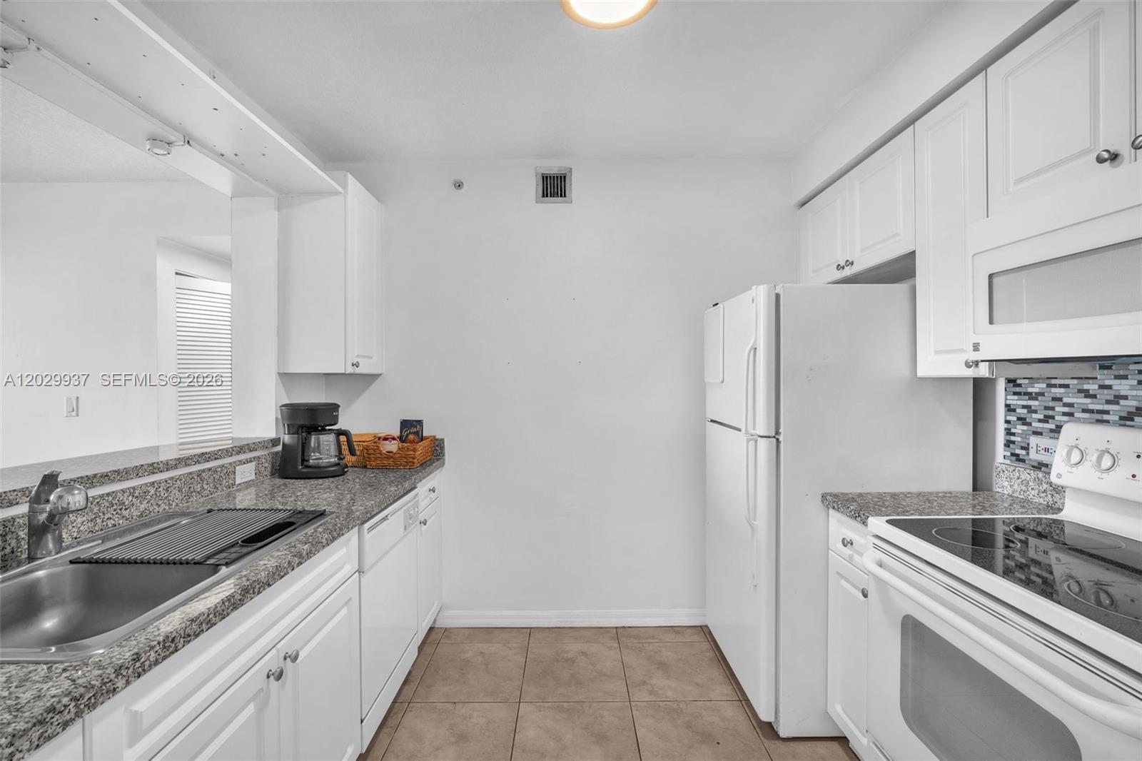 A kitchen features white cabinets, granite countertops, a white refrigerator, and a white electric stove — 900 SW 8th St # 1103, Miami FL 33130, MIAMI, FL