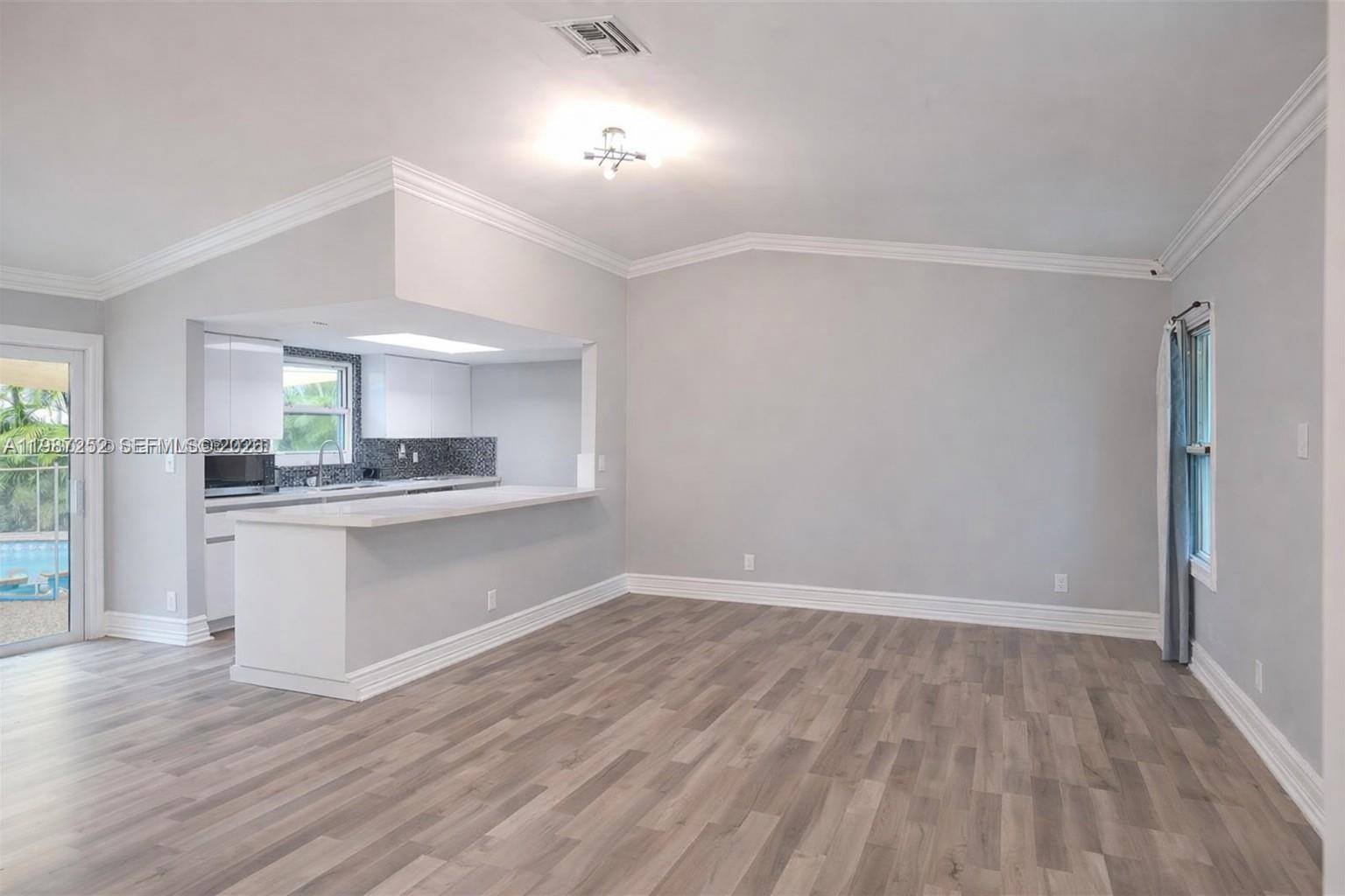 An open-concept living area features light gray walls, wood-look flooring, and a kitchen pass-through — 4541 SW 28th Ter, Dania Beach FL 33312, DANIA BEACH, FL