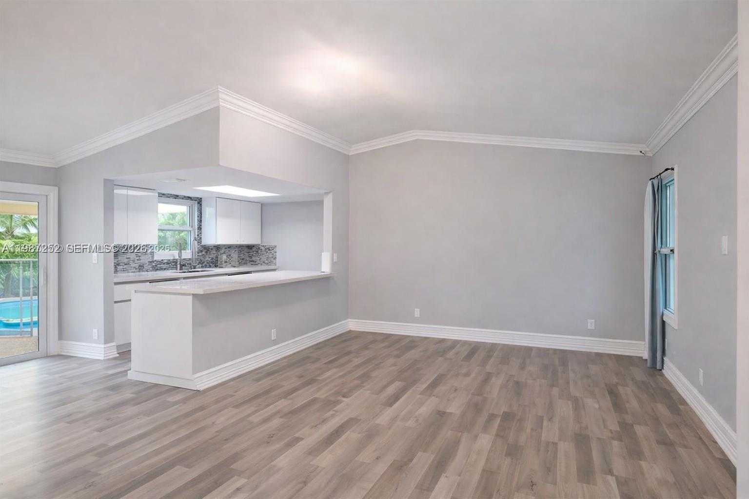An open-concept living area features light gray walls, wood-look flooring, and a kitchen pass-through window — 4541 SW 28th Ter, Dania Beach FL 33312, DANIA BEACH, FL