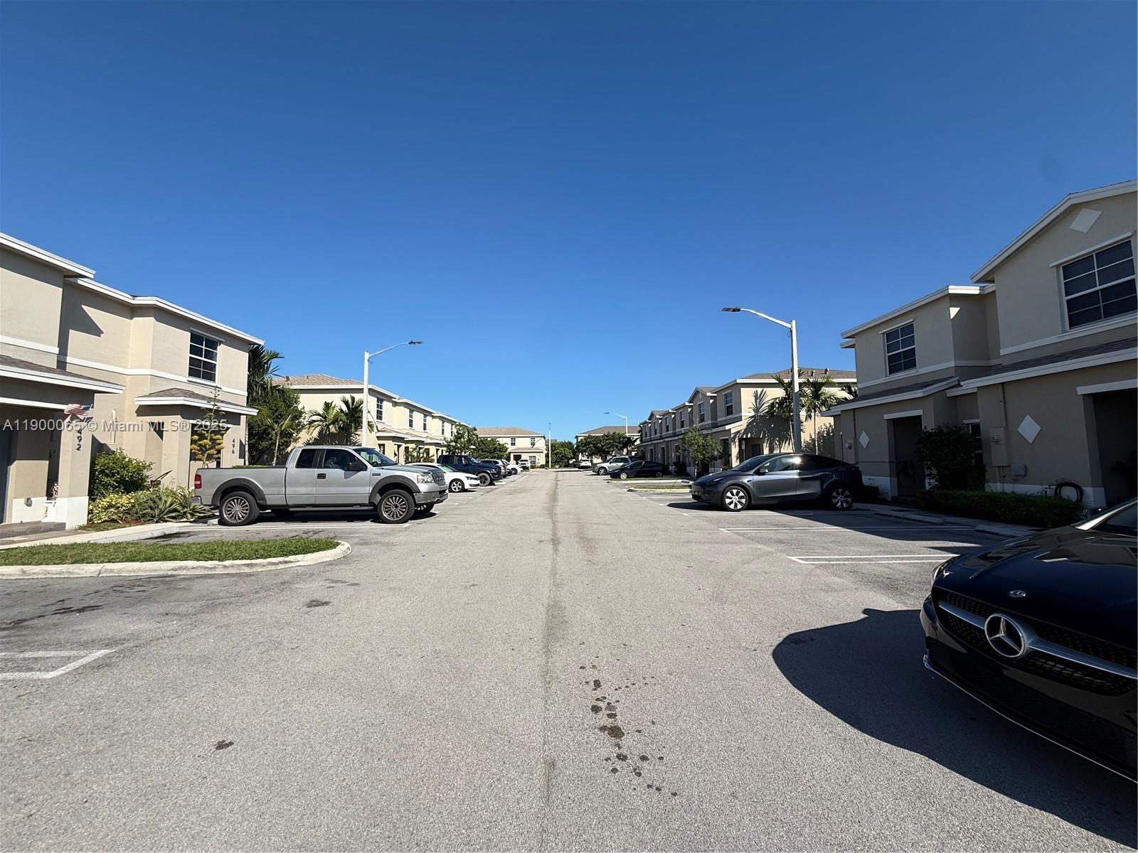 A street view of a residential complex with parked cars and multi-story townhomes — 484 NE 5th St, Florida City FL 33034, FLORIDA CITY, FL