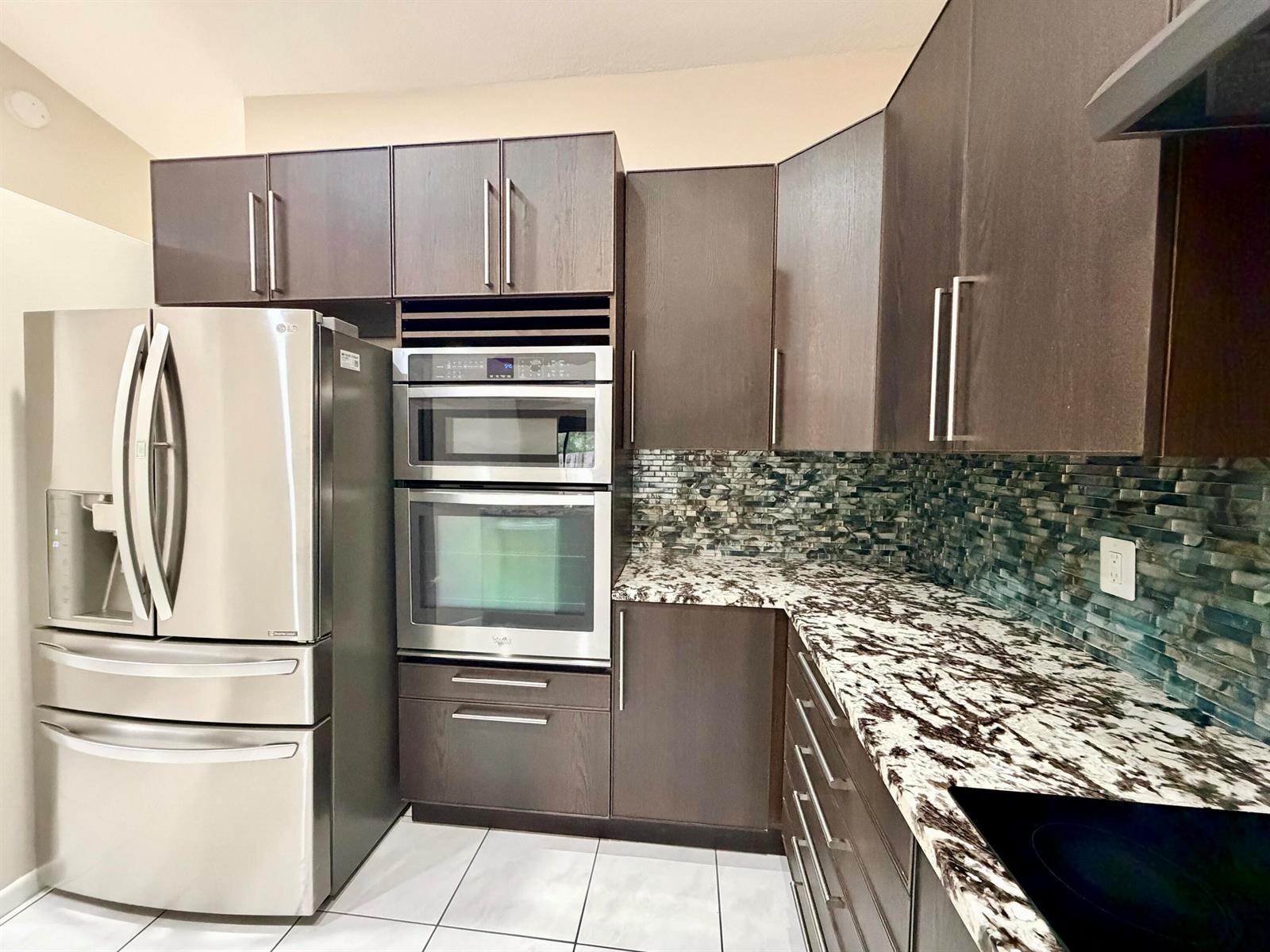 A kitchen features dark wood cabinets, stainless steel appliances, and a patterned granite countertop — 11137 NW 38th Place, Sunrise FL 33351, SUNRISE, FL