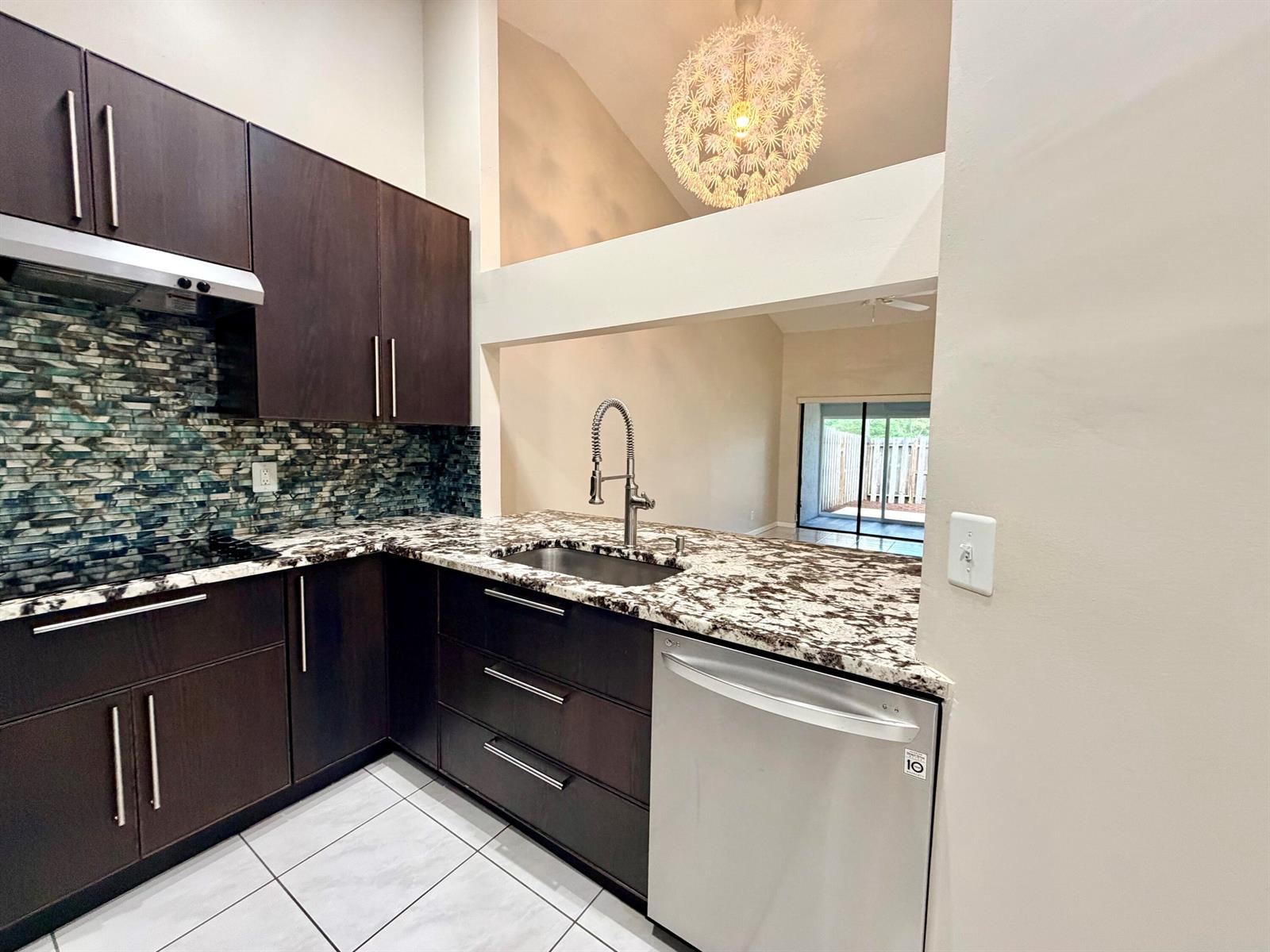 A kitchen features dark wood cabinets, granite countertops, a mosaic backsplash, and stainless steel appliances — 11137 NW 38th Place, Sunrise FL 33351, SUNRISE, FL