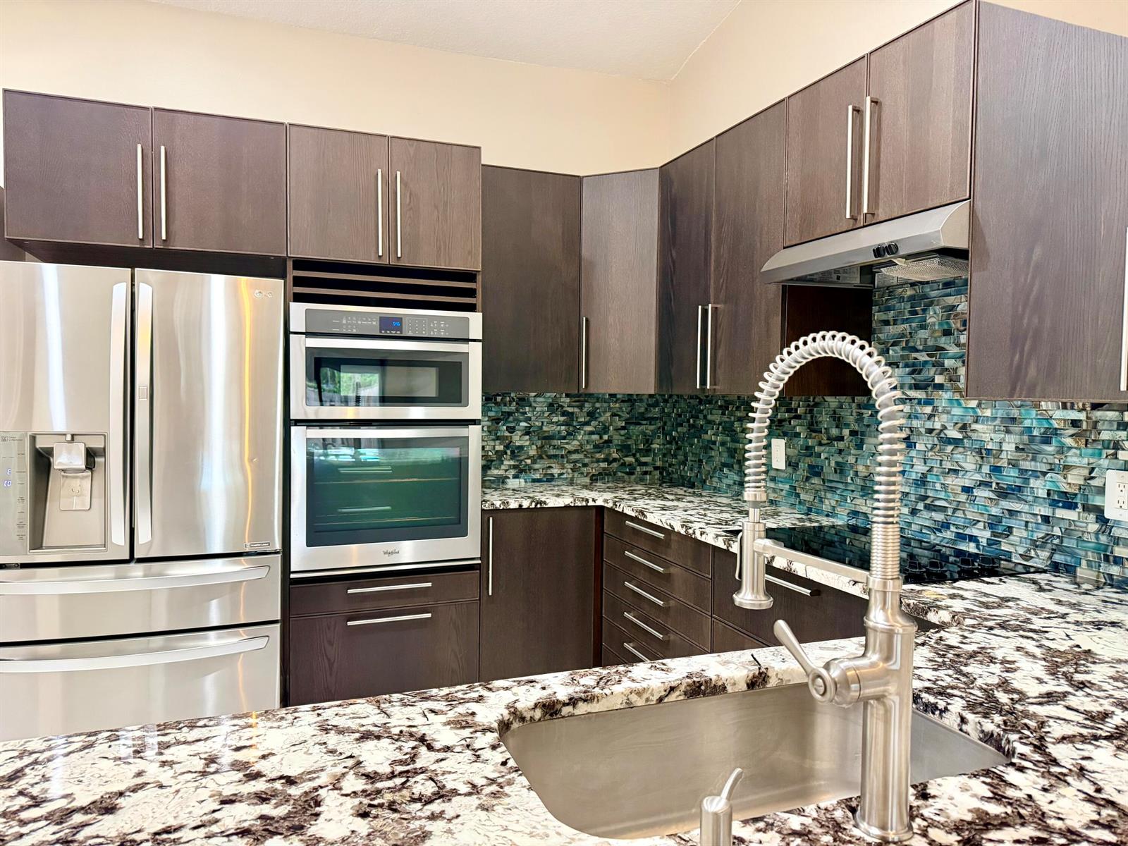 A kitchen features dark wood cabinets, stainless steel appliances, granite countertops, and a blue backsplash — 11137 NW 38th Place, Sunrise FL 33351, SUNRISE, FL