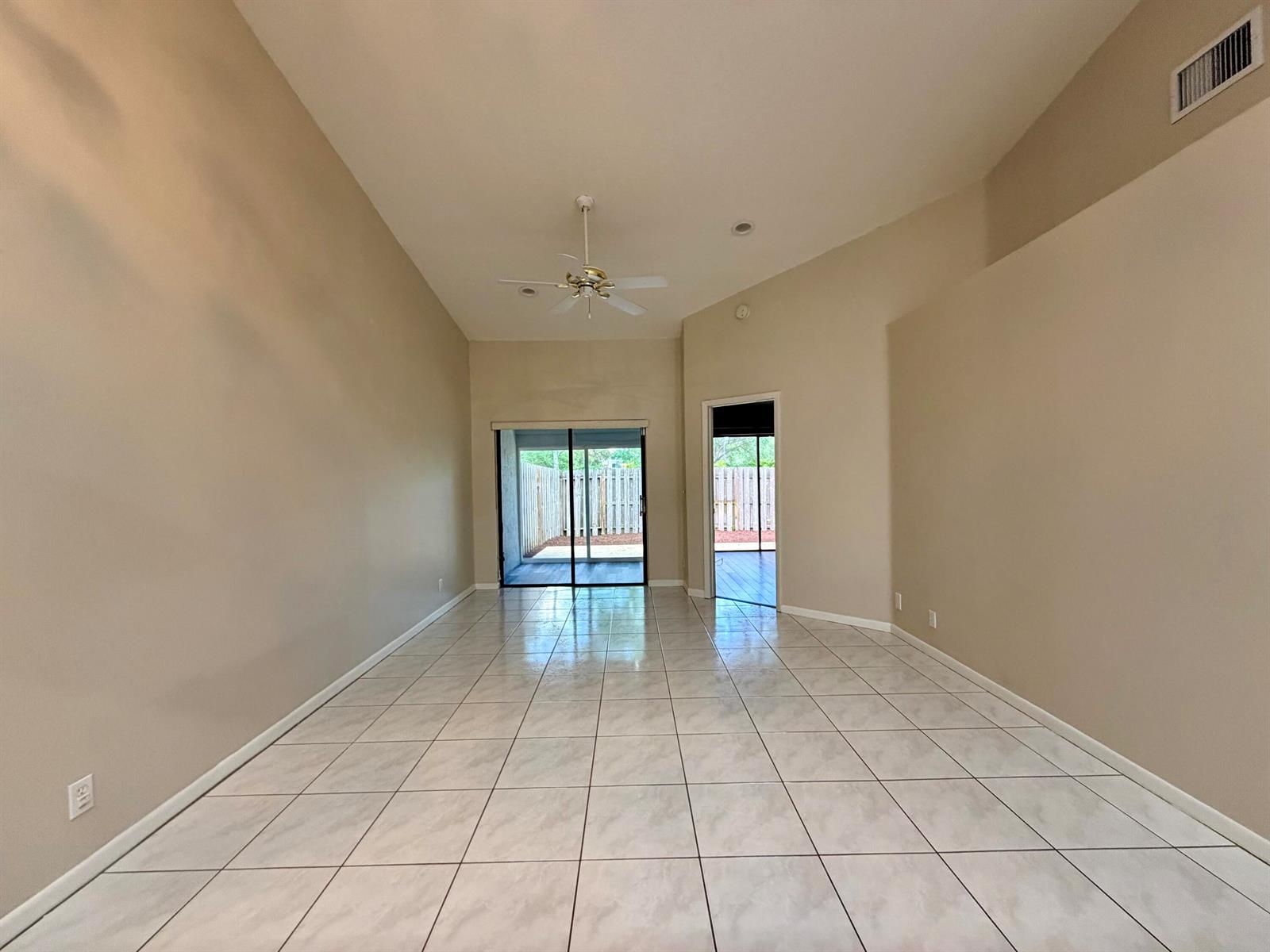 An empty room with light-colored tile flooring, vaulted ceilings, a ceiling fan, and sliding doors — 11137 NW 38th Place, Sunrise FL 33351, SUNRISE, FL