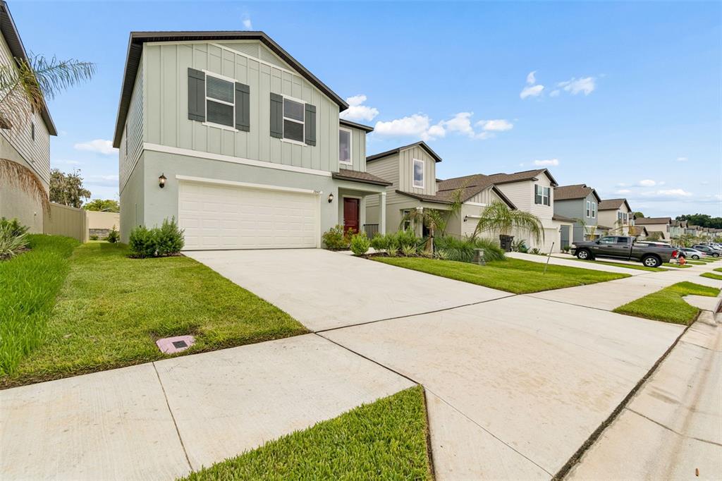 A two-story house with light green siding and a two-car garage sits on a street — 7847 ABAGAIL DRIVE, LAKELAND, FL