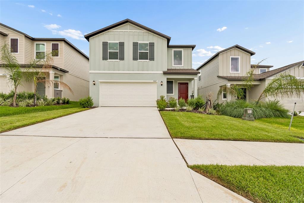 A two-story suburban house features a light green exterior, a two-car garage, and a driveway — 7847 ABAGAIL DRIVE, LAKELAND, FL