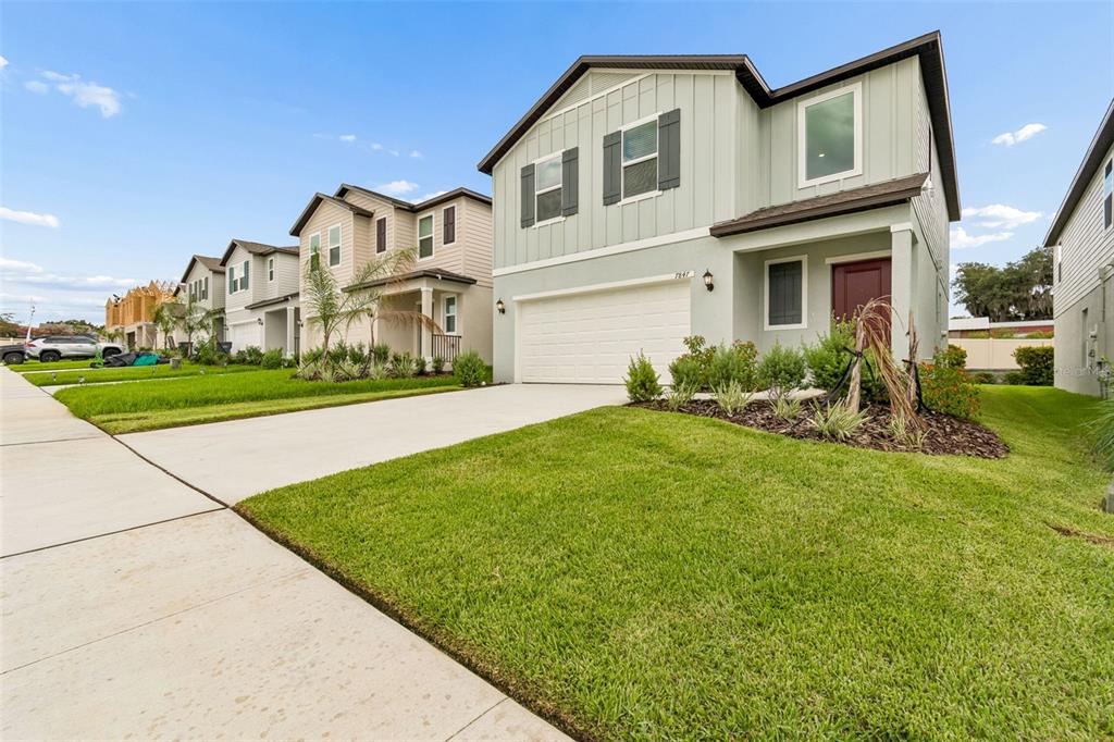 A two-story suburban house with light green siding, a two-car garage, and a front lawn — 7847 ABAGAIL DRIVE, LAKELAND, FL
