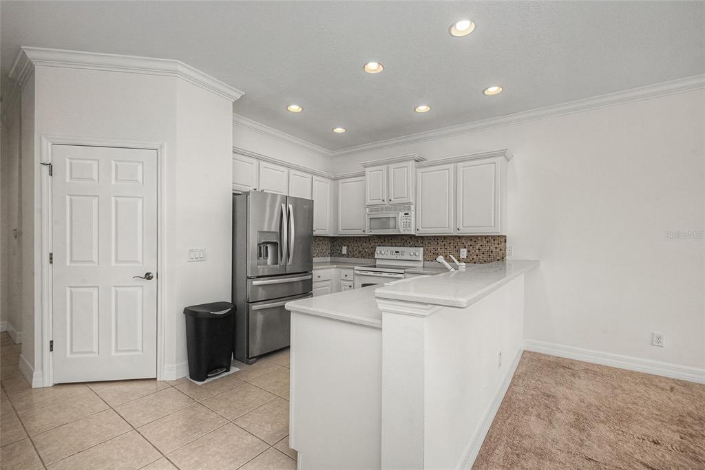 A kitchen with white cabinets, stainless steel appliances, tile flooring, and a breakfast bar — 11443 52ND COURT E, PARRISH, FL