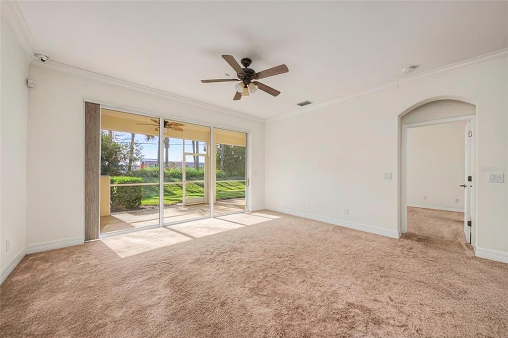 An empty room with beige carpet, a ceiling fan, and sliding glass doors to a patio — 11443 52ND COURT E, PARRISH, FL