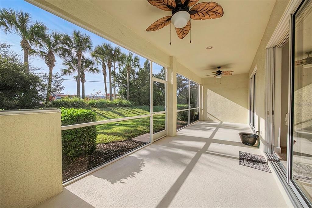 A screened-in patio with a concrete floor, two ceiling fans, and a view of palm trees — 11443 52ND COURT E, PARRISH, FL