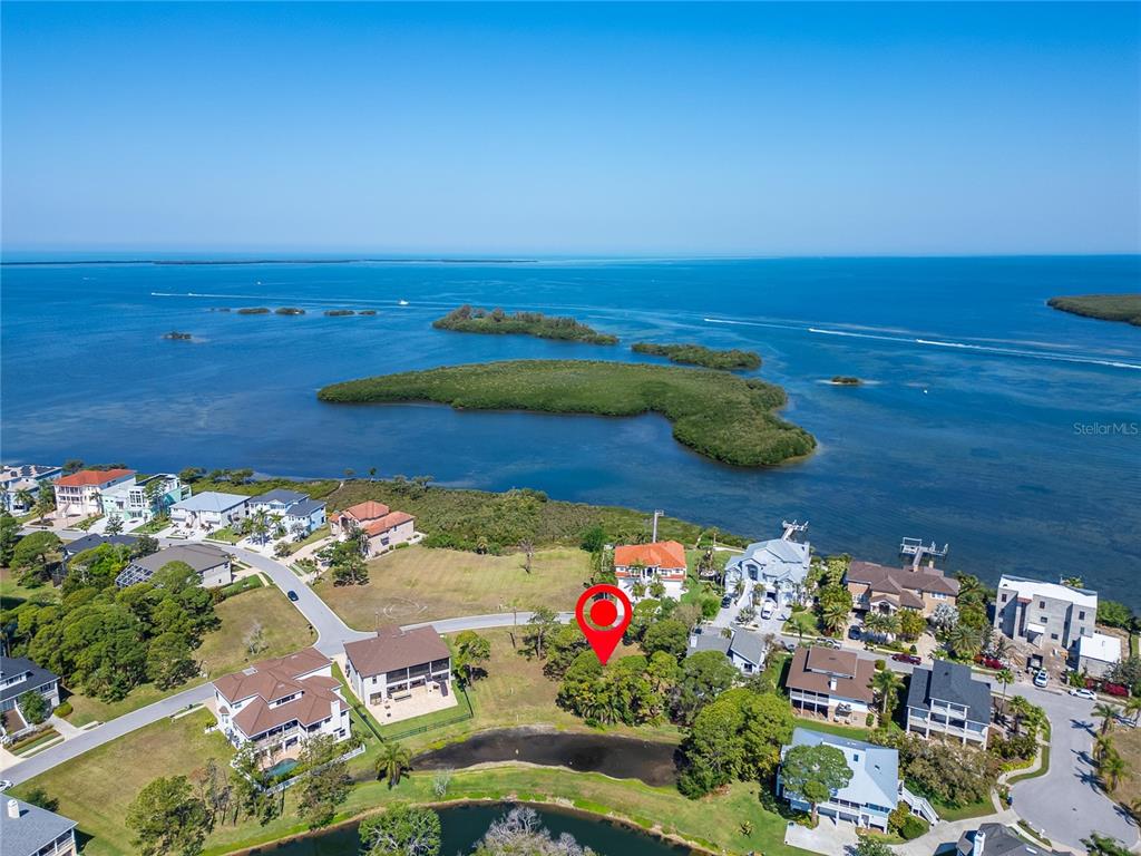 An aerial view shows a vacant lot marked with a red pin near a waterfront — N POINTE ALEXIS DRIVE, TARPON SPRINGS, FL