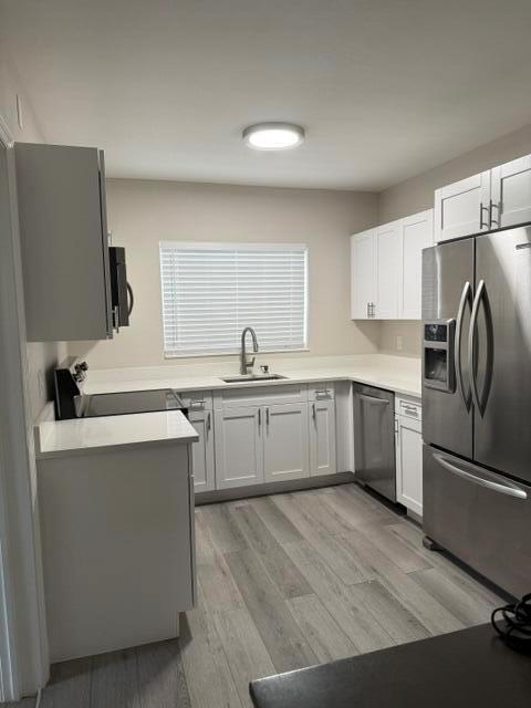 A modern kitchen features white cabinets, stainless steel appliances, and light wood-look flooring — 112 Lake Avenue # 5, FL 33460, FL