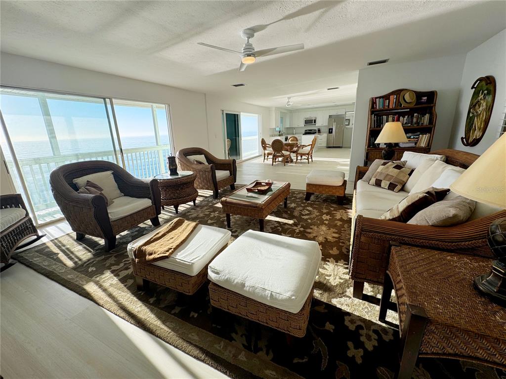 A living room with wicker furniture and a rug overlooks the ocean through sliding doors — 6780 MANASOTA KEY ROAD, ENGLEWOOD, FL