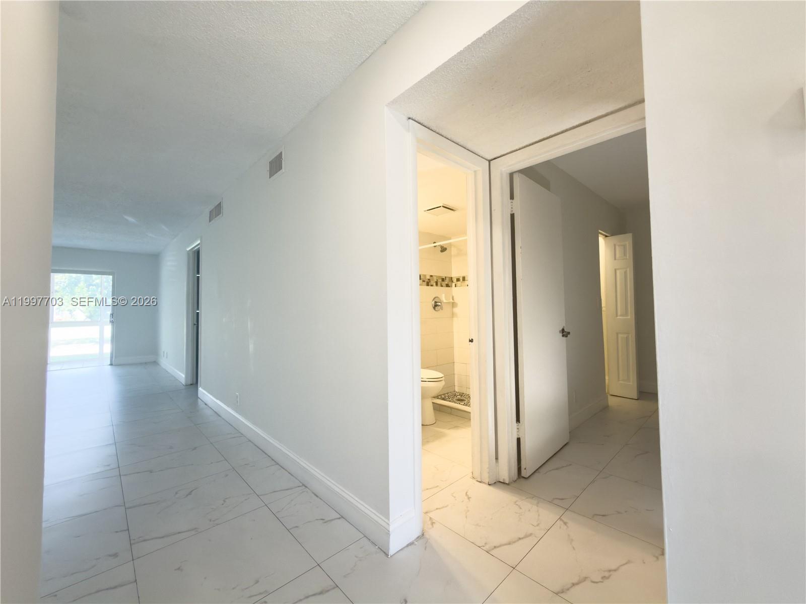 A kitchen features white cabinets, quartz countertops, a white refrigerator, and tiled flooring — 605 S State Road 7 # 1D, Margate FL 33068, MARGATE, FL