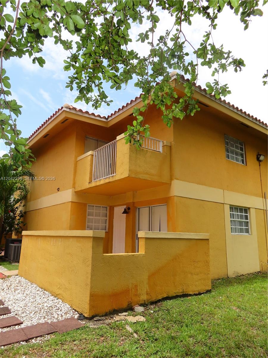A two-story yellow stucco building features a small balcony and a ground-level patio area — 13894 SW 65th Ter # 12, Miami FL 33183, MIAMI, FL