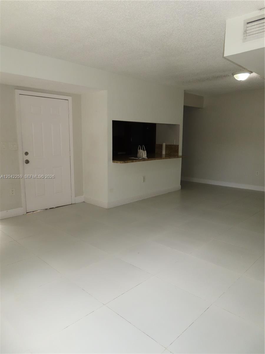 An interior view shows a room with white tile floors, a white door, and a pass-through window — 13894 SW 65th Ter # 12, Miami FL 33183, MIAMI, FL