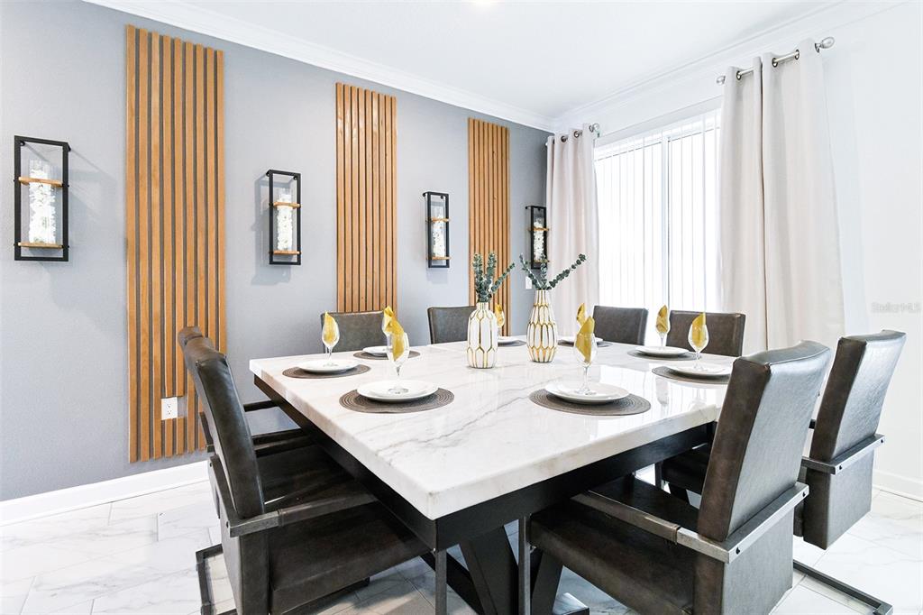 A dining room features a square marble table, dark chairs, and vertical wood slat wall accents — 3011 PENELOPE LOOP, KISSIMMEE, FL