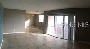 An open-concept living area features light-colored tile flooring and a sliding glass door — 3984 VERSAILLES DRIVE UNIT 3984C, ORLANDO, FL