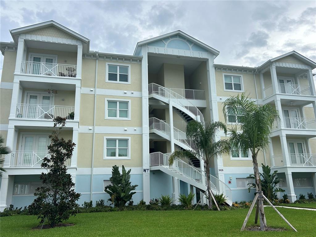 A three-story apartment building features exterior staircases, balconies, and light-colored stucco siding — 3426 79TH STREET CIRCLE W UNIT 203, BRADENTON, FL