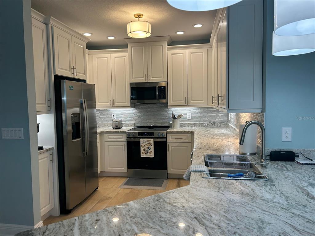 A kitchen features white cabinets, stainless steel appliances, and light-colored granite countertops — 3426 79TH STREET CIRCLE W UNIT 203, BRADENTON, FL