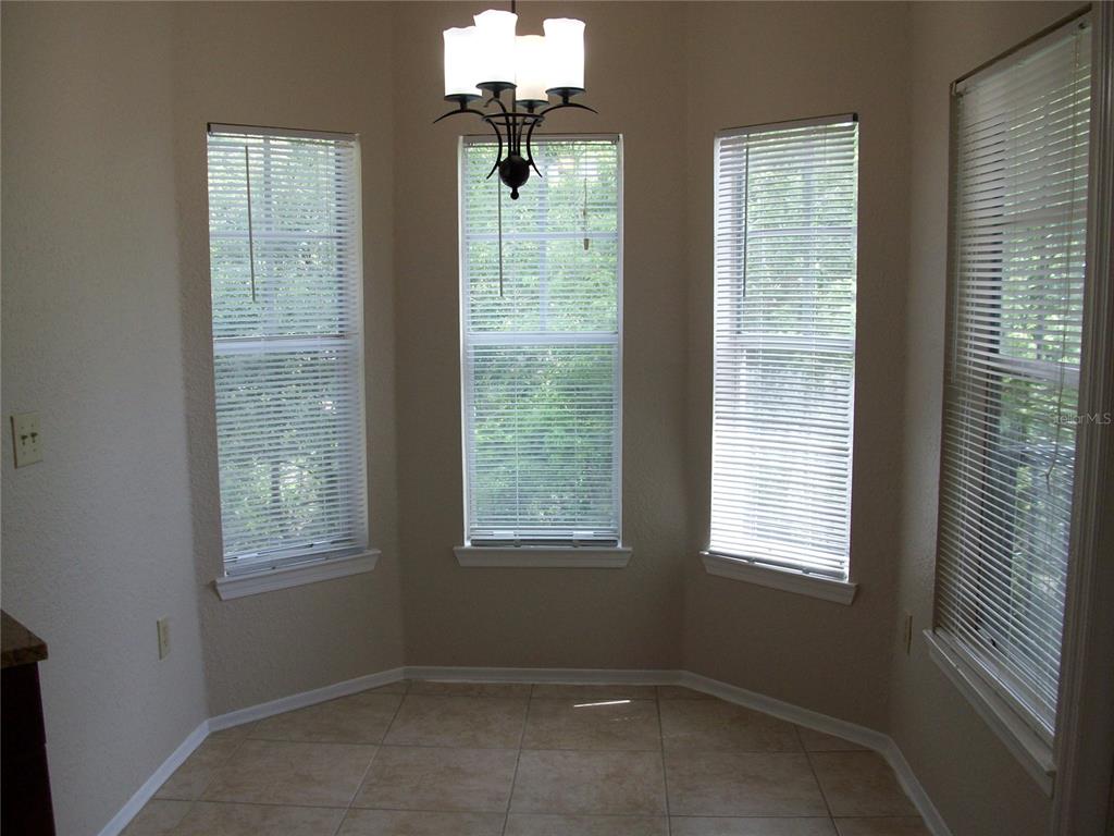 A dining nook features tile flooring, a chandelier, and three windows with white blinds — 143 VILLA DI ESTE TERRACE UNIT 205, LAKE MARY, FL