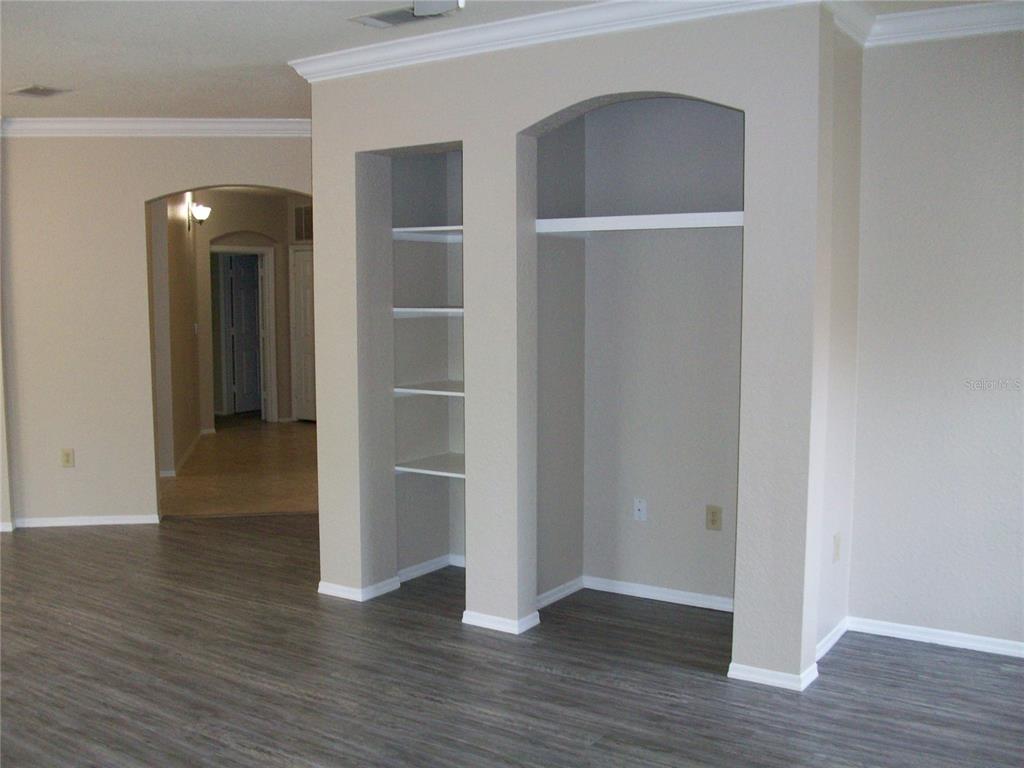 An interior view shows a living area with arched built-in shelving and wood-look flooring — 143 VILLA DI ESTE TERRACE UNIT 205, LAKE MARY, FL
