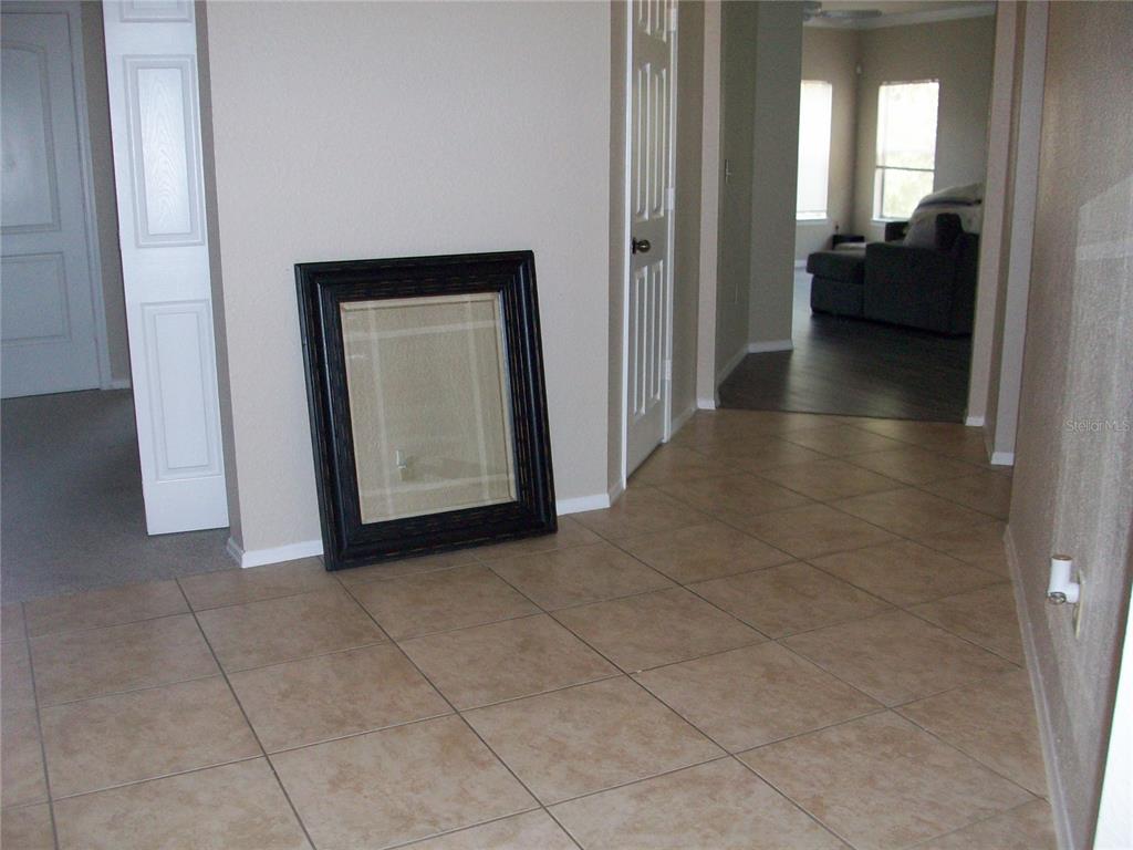 A tiled entryway features a large framed mirror leaning against a beige wall — 143 VILLA DI ESTE TERRACE UNIT 205, LAKE MARY, FL