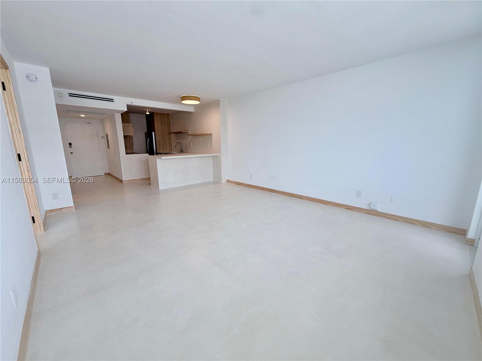 An open-concept living area features light-colored flooring, white walls, and a small kitchen island — 100 Lincoln Rd # 1241, Miami Beach FL 33139, MIAMI BEACH, FL