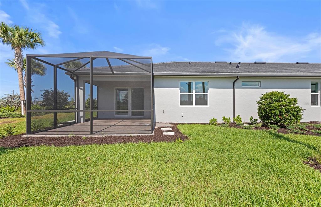 The exterior of a house features a screened-in patio, a grassy yard, and a palm tree — 27112 CLAM SHELL COURT, ENGLEWOOD, FL