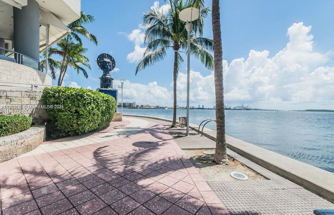 A paved waterfront walkway features palm trees, a sculpture, and a view of the bay — 325 S Biscayne Blvd # 3822, Miami FL 33131, MIAMI, FL