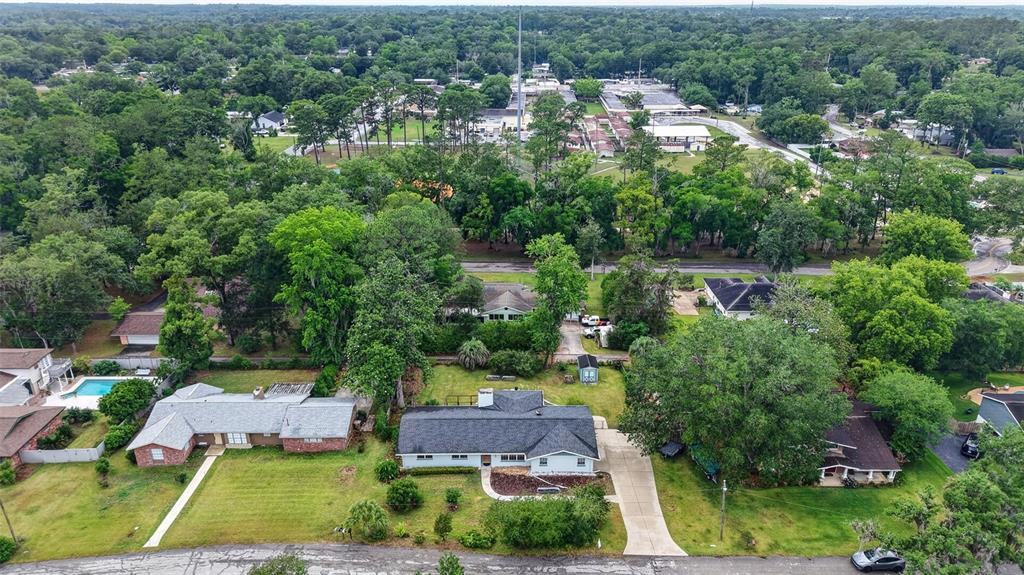 An aerial view shows several suburban houses with large yards surrounded by dense green trees — 550 SE 39TH TERRACE, OCALA, FL