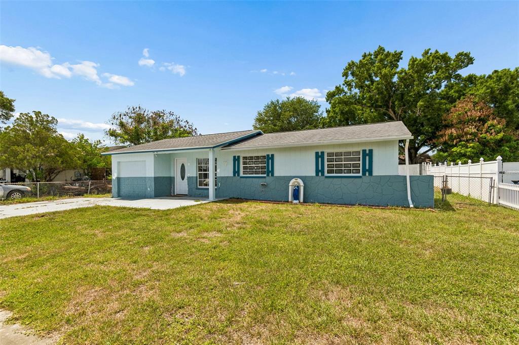 A single-story house with a two-tone exterior, a front lawn, and a white fence — 1719 JULIAN LANE DRIVE, TAMPA, FL
